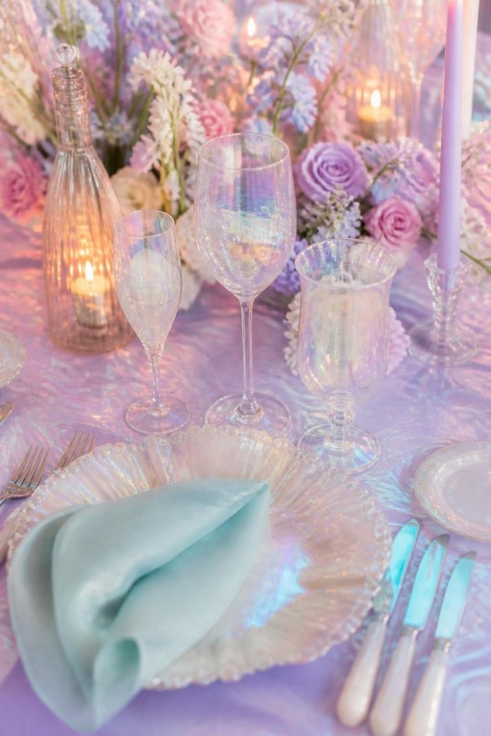 Opal-toned iridescent glassware and pearlescent chargers on a lilac and aqua reception table in soft candlelight